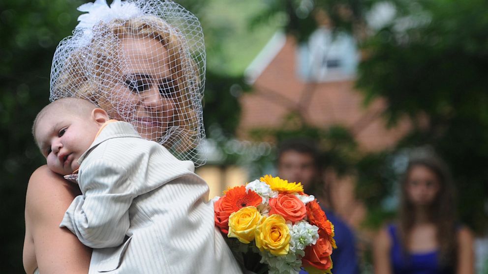 PHOTO: Christine Swidorsky carries her son and the couples best man, Logan Stevenson, 2, down the aisle to her husband-to-be Sean Stevenson during the wedding ceremony on Aug. 3, 2013 in Jeannette, Pa.