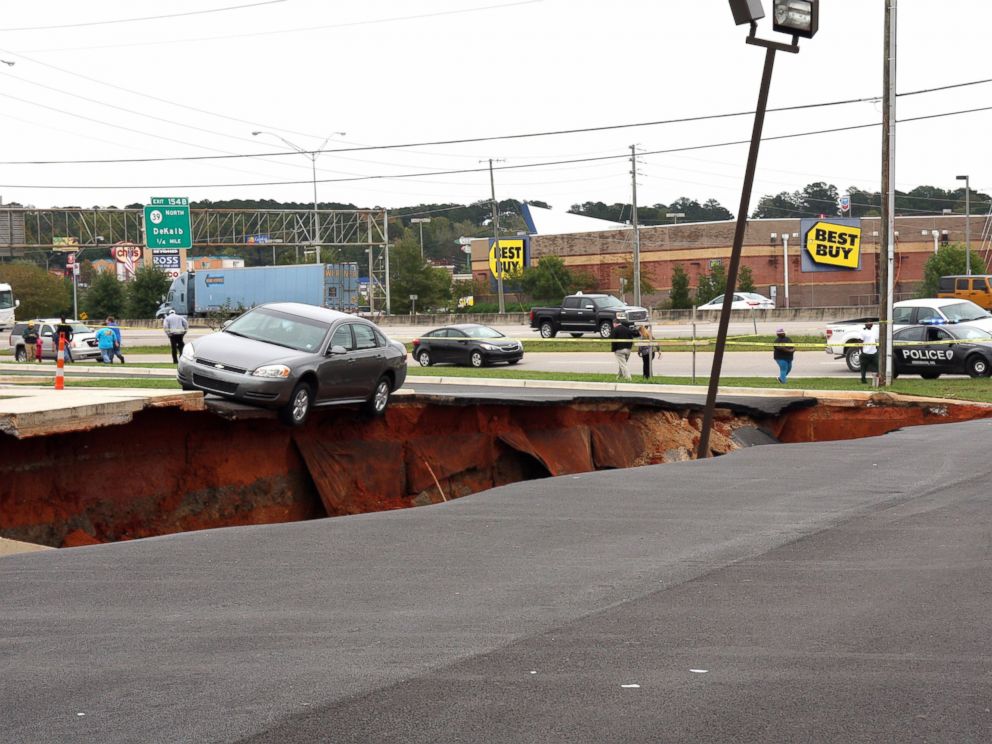 PHOTO: A car teeters on the edge of a cave-in of a parking lot in Meridian, Miss., Sunday, Nov. 8, 2015.