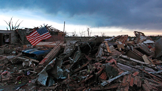 PHOTO: An American flag blows in the wind at sunrise atop the rubble of a destroyed home in Moore, Okla., on May 21, 2013, a day after a tornado roared through the Oklahoma City suburb, flattening entire neighborhoods and destroying an elementary school w