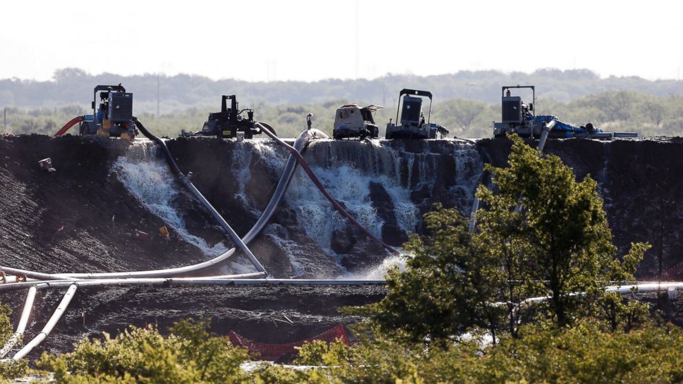 PHOTO: Workers attempt to relieve the pressure from the earthen dam at Padera Lake, May 27, 2015, in Midlothian, Texas.
