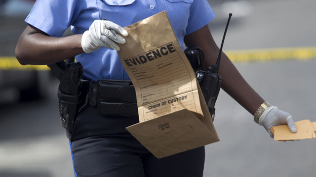 PHOTO: New Orleans police officer collects evidence at the scene of a shooting at the intersection Frenchman Street at N. Villere on Mothers Day in New Orleans, Sunday May 12, 2013.