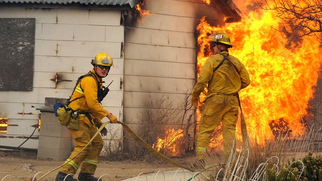 PHOTO: Firefighters wait for water before attacking an outbuilding adjacent to a home, Jan. 19, 2012 in Pleasant Valley, Nev.
