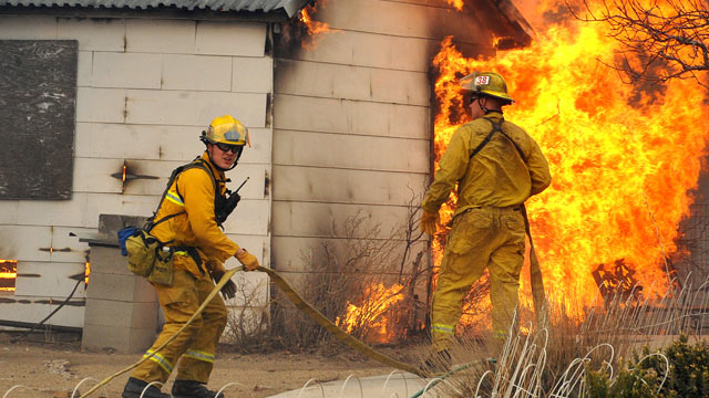 PHOTO: Firefighters wait for water before attacking an outbuilding adjacent to a home, Jan. 19, 2012 in Pleasant Valley, Nev.