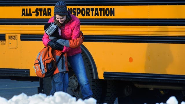 PHOTO: A woman hugs a child before he boards a bus on the first day of classes after the holiday break, in Newtown, Conn., Jan. 2, 2013.