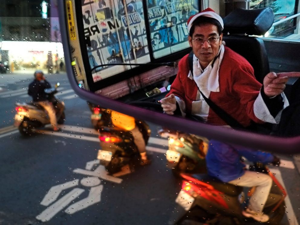 PHOTO: Reflected in a mirror, a public bus driver dressed as Santa Claus gives a passenger directions on Dec. 18, 2013, in Taipei, Taiwan.
