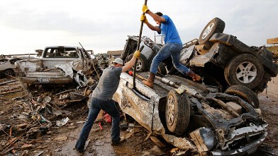 PHOTO: Two men attempt  to pry open a door on this car to check for victims in a business parking lot west of I-35 south of 4th Street  in Moore, on  May 20, 2013.