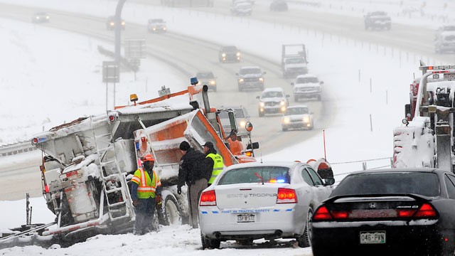 PHOTO: Police and road workers inspect the scene where a snow plow slid off the road along Route C470 in the Denver suburb of Morrison, Colo., Dec. 22, 2011.