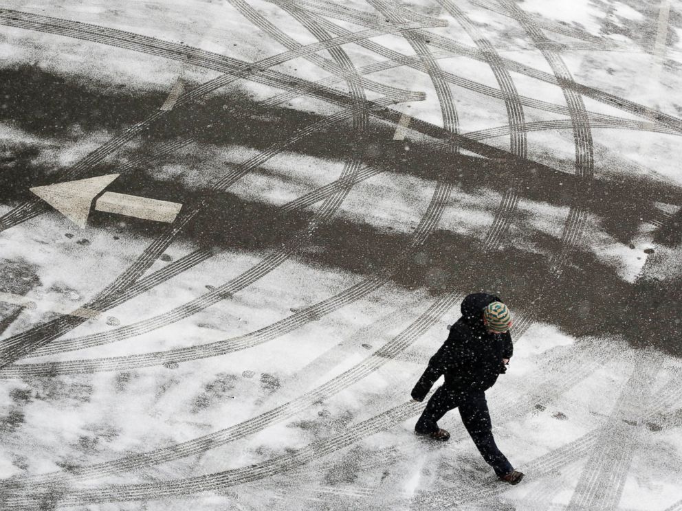 PHOTO: A pedestrian crosses a snowy parking lot before heavy snowfall arrives, Jan. 26, 2015, in New York.