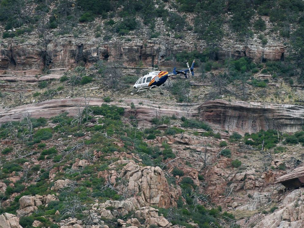 PHOTO: A helicopter flies above the rugged terrain along the banks of the East Verde River during a search and rescue operation for victims of a flash flood, July 16, 2017, in Payson, Ariz.