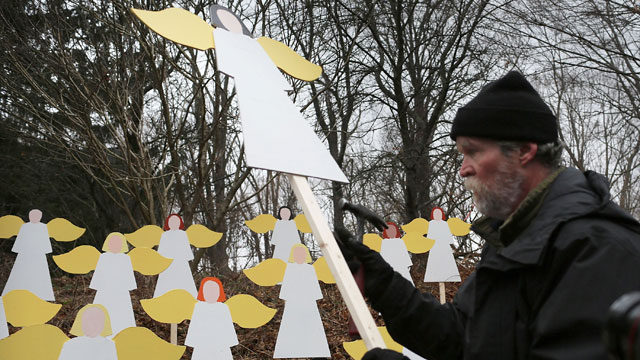 PHOTO: Eric Mueller places twenty seven wooden angles he made in his yard down the street from the Sandy Hook School on Dec. 16, 2012 in Newtown, Conn.
