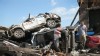 Eric Lowery looks over damage to his mother's vehicle after it was blown from her workplace and came to rest on the debris of a nearby collapsed building in Moore, Okla., May 23, 2013.