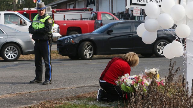 PHOTO: A police officer keeps watch as a woman kneels at a makeshift memorial outside a firehouse which was used as a staging area for families following the mass shooting at Sandy Hook Elementary School on December 15, 2012 in Newtown, Connecticut.