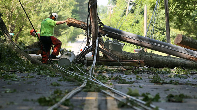 PHOTO: Workers cut up a fallen tree, so that power lines can be repaired, on June 30, 2012 in Huntington, Maryland.