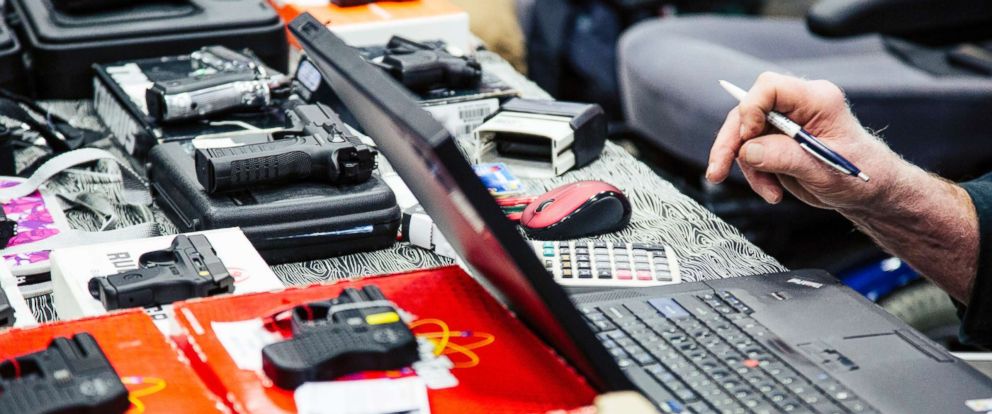 PHOTO: A purveyor does some pricing calculations while a customer fills out their background check materials before purchasing a handgun at a gun show at the Augusta Civic Center in Augusta, Maine, Jan. 16, 2016.