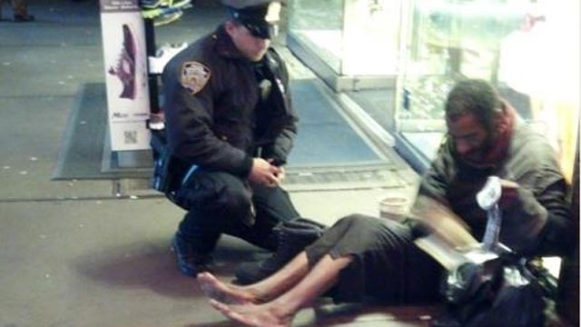 PHOTO: An NYPD officer gives a shoeless homelsess man a pair of boots in New York City, Nov. 27, 2012.