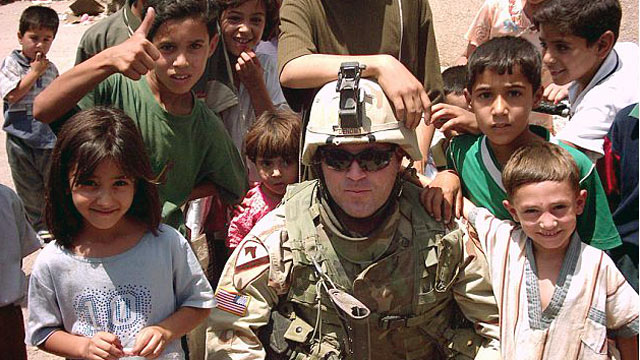 PHOTO: Then-Cpt. Troy Denomy poses for a photo with children in Iraq.