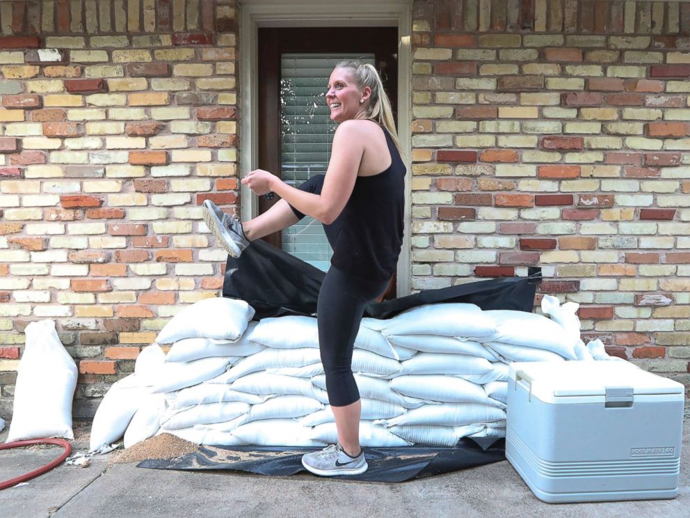 PHOTO: Lacey Williams exits the only door she can by stepping over sandbags that surround her home in Houston Aug. 24, 2017. 