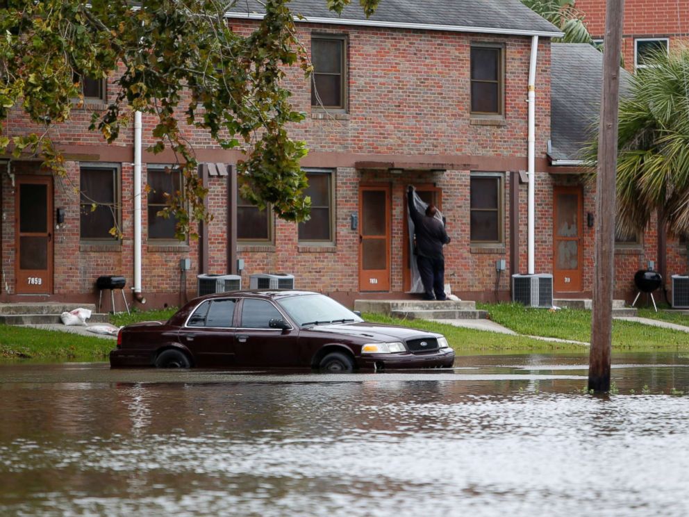 PHOTO: A Charleston, S.C. resident puts plastic up over his apartment door as a car rests in floodwaters near East Bay Street in Charleston, S.C., Sept. 10, 2017.