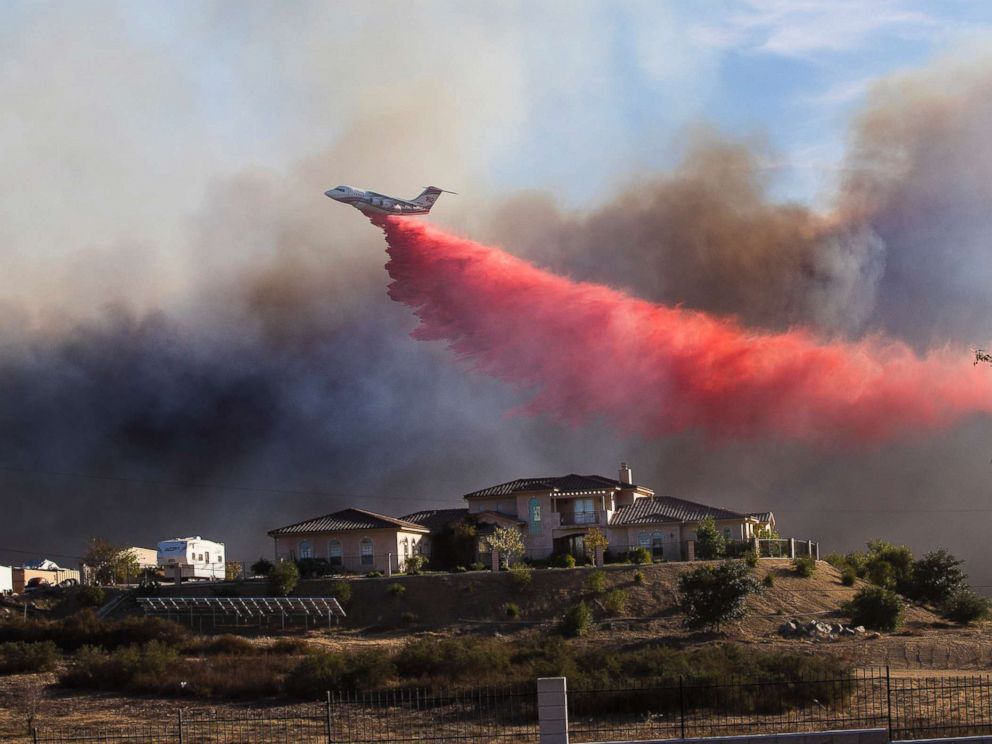 PHOTO: A plane drops fire retardant near a home to stop the wind driven Liberty Fire near Los Alamos Road on Dec. 7, 2017 in Murrieta, Calif.