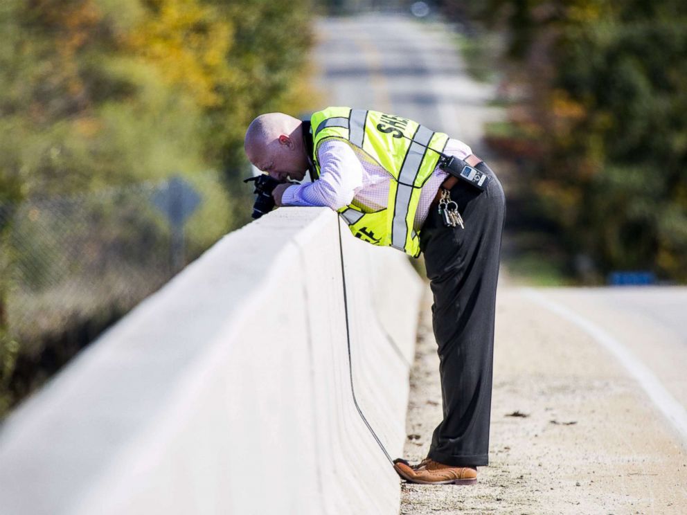 Genesee County Sheriffs Office investigator takes photos from an overpass on Oct. 20, 2017, in Vienna Township, Mich. where a rock was thrown from, smashing a car windshield and killing a 32-year-old man on Oct. 18.