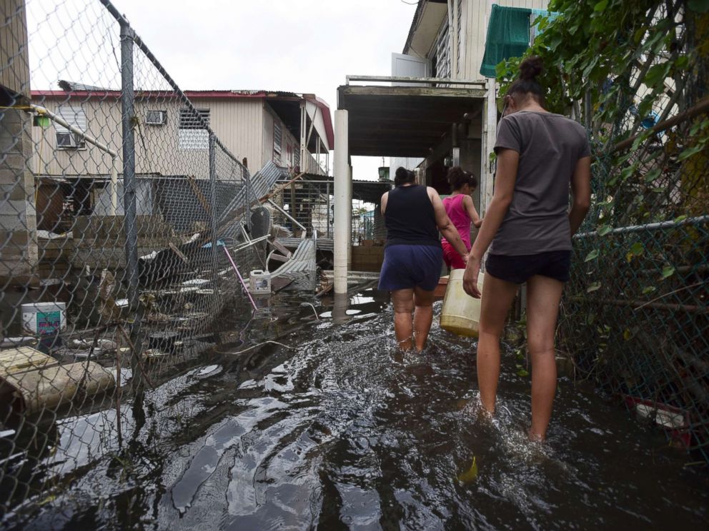 PHOTO: Residents wade through a flooded area in the aftermath of Hurricane Maria, in Catano, Puerto Rico, Sept. 27, 2017.