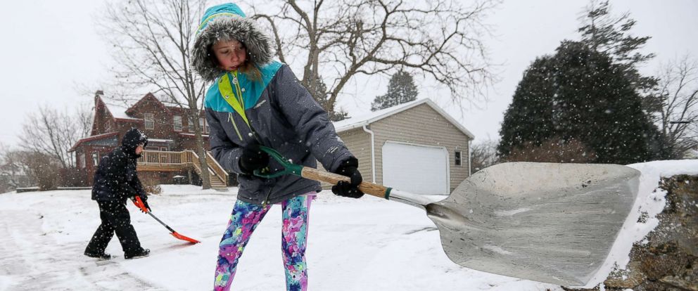 PHOTO: Karlee Winter, 11, and her brother Samuel Espinoza, 8, shovel snow from their neighbors sidewalk in Dubuque, Iowa, Dec. 28, 2017. 