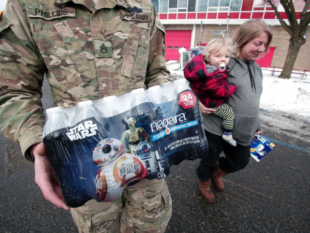 PHOTO:Michigan National Guard Staff Sergeant William Phillips of Birch Run, Mich., helps Flint resident Amanda Roark and her son Dash take bottled water out to her vehicle after she received it at a Flint Fire Station, Jan. 13, 2016, in Flint, Mich.