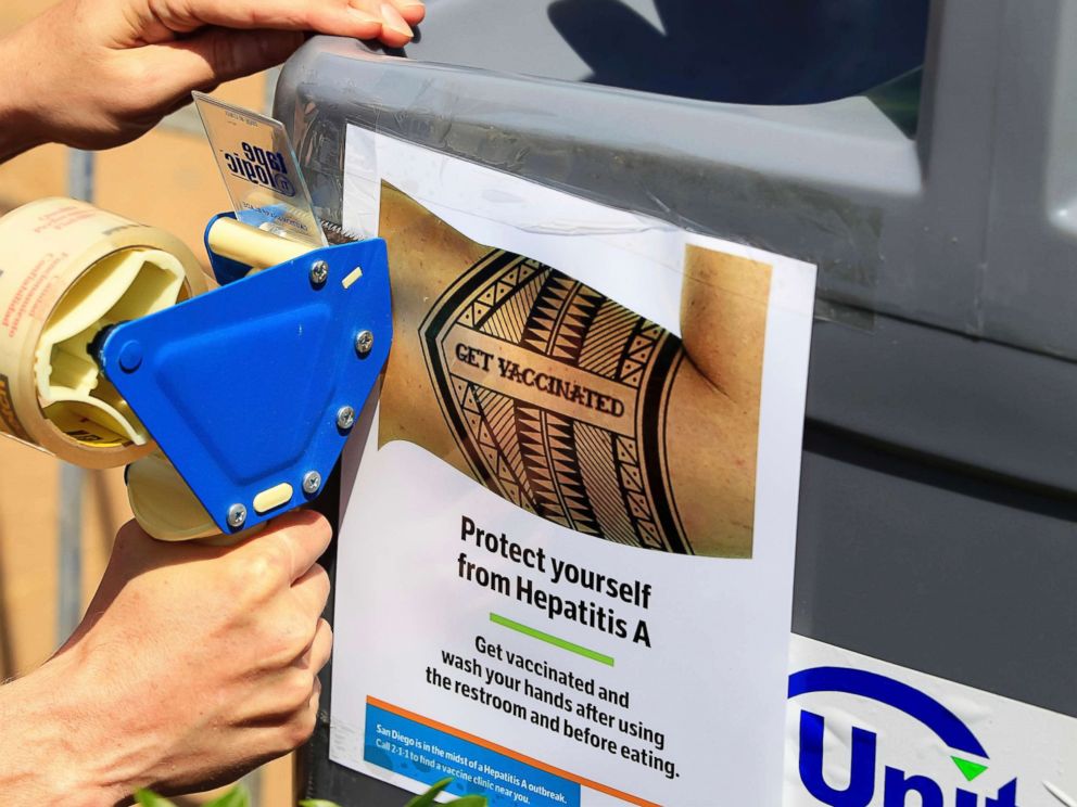 PHOTO: A worker tapes signage telling people to get vaccinated to protect themselves against hepatitis A on hand washing sinks installed at the Neil Good Day Center in downtown San Diego, Sept. 1, 2017.