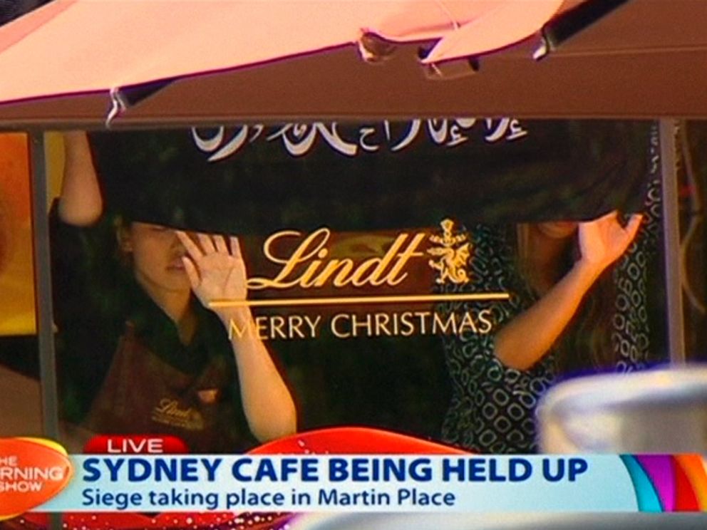 PHOTO: This image taken from video show people holding up what appeared to be a black flag with white Arabic writing on it, inside a cafe in Sydney, Australia, Dec. 15, 2014. 