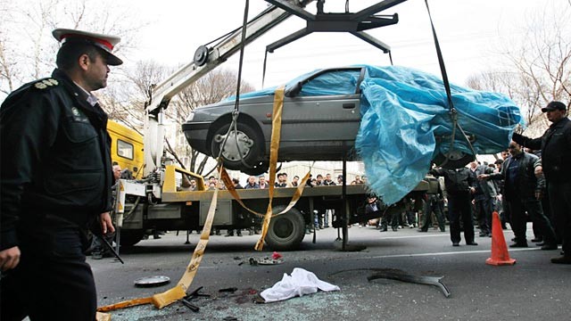 PHOTO: People gather around a car as it is removed by a mobile crane in Tehran, Iran, Jan. 11, 2012.