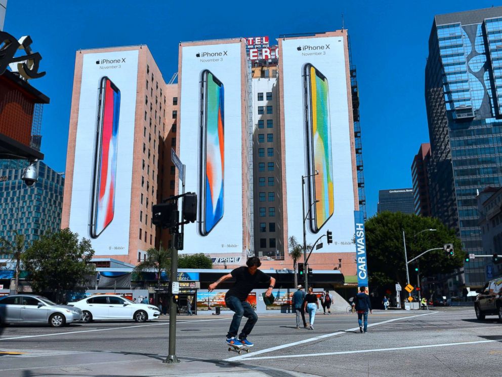 PHOTO: A skateboarder jumps the curb crossing a street in Los Angeles on Oct. 13, 2017, where advertising for Apples new iPhone X, due for release on November 3, covers the sides of three buildings.