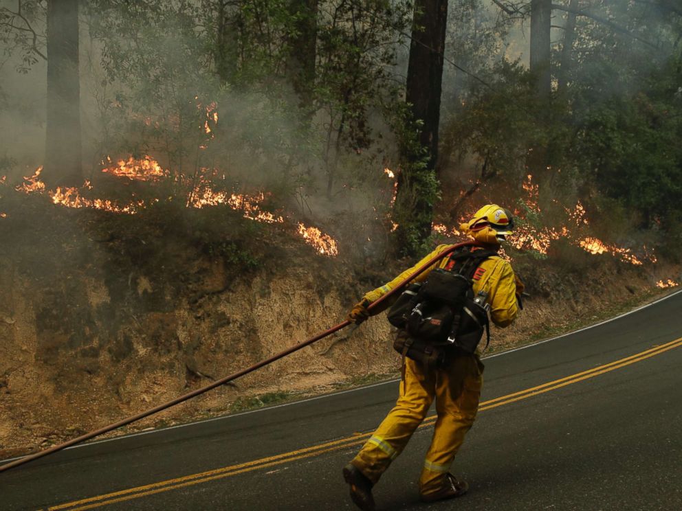 PHOTO: Firefighter David Allhiser carries a water hose to put out a fire, Oct. 12, 2017, near Calistoga, Calif.